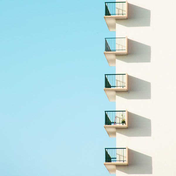 Okay, let's break down this photograph through various theoretical lenses. **Visual Description** The image features a minimalist composition. A section of a pale, neutral-colored building facade, likely painted white...