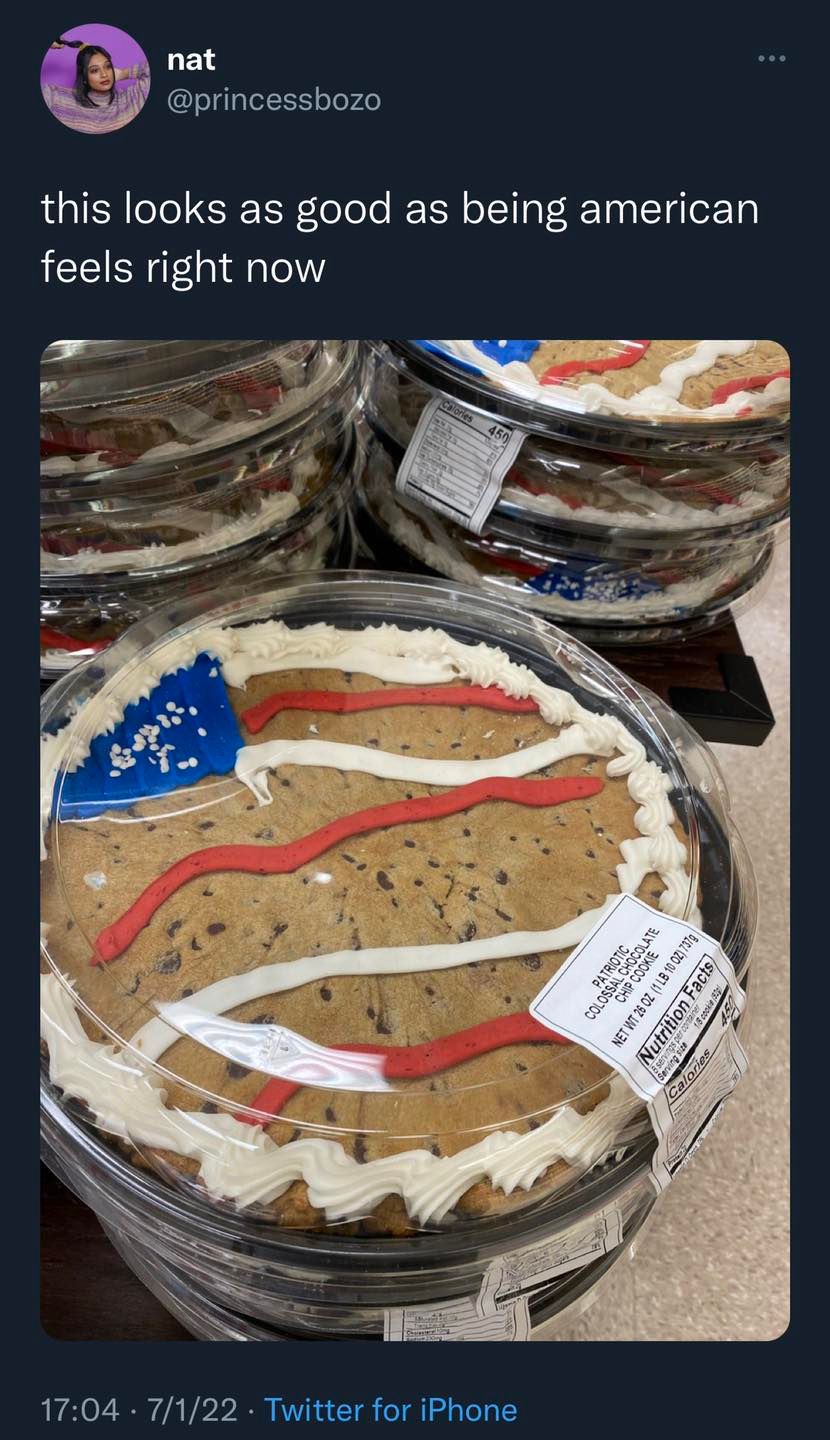 This meme is a photo of a cookie cake decorated to look like the American flag, with red, white, and blue frosting. The text above the image reads "this looks as good as being american feels right now". The meme is likely referencing the idea that the cookie cake's patriotic design is a symbol of American culture and values, but also implies that being American is not always a positive or fulfilling experience.