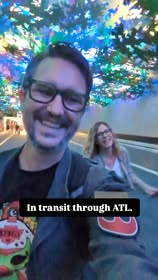 Okay, let's break down the image with analyses where applicable. **Visual Description** The image appears to be a selfie taken indoors, likely in an airport or transportation hub (given the text "In transit through AT...