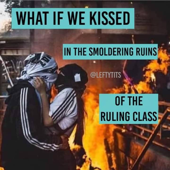 The meme is a humorous take on a hypothetical situation where a couple would react if they were in a classroom and kissed in the middle of a lesson. The text "WHAT IF WE KISSED IN THE SMOLDERING RUINS OF THE SCHOOL" is overlaid on an image of a couple embracing in front of a burning building.