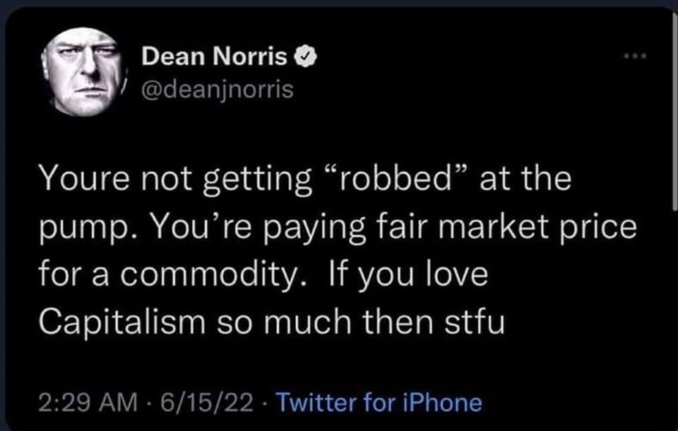The meme is a screenshot of a tweet by Dean Norris, a comedian and actor. The text reads: "You're not getting robbed at the pump. You're paying fair market price for a commodity. If you love capitalism so much, then STFU." The image is a humorous take on the common complaint about high gas prices, with Norris sarcastically defending the idea that people are being "robbed" at the pump.