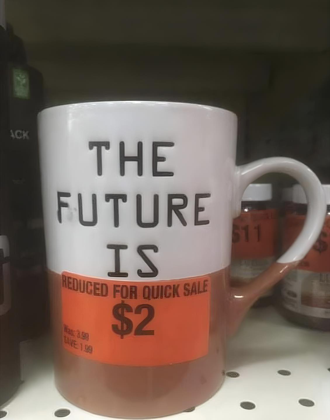 This meme is a humorous image of a coffee mug with a price tag that reads "THE FUTURE IS $2.99" crossed out and replaced with "THE FUTURE IS $2". The image is likely meant to be ironic or satirical, implying that the future is now a cheap and affordable thing.