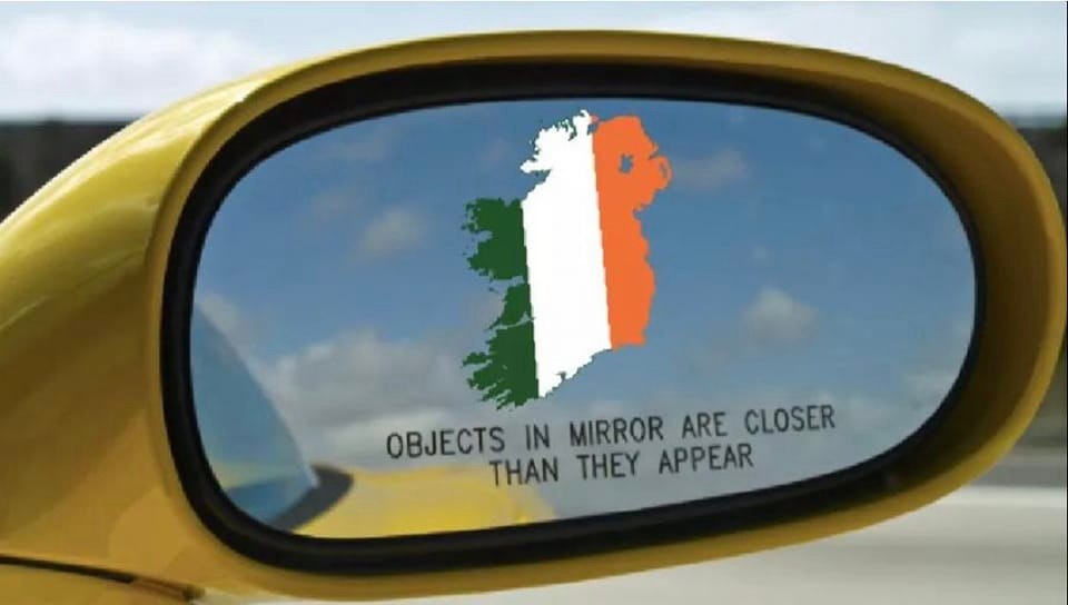 This meme is a play on the "objects in mirror are closer than they appear" warning sticker found in rearview mirrors. However, it's been altered to say "objects in mirror are closer than they appear" in a way that's intentionally misleading. The image shows a modified version of this sticker with the words "objects in mirror are closer than they appear" but with a "U" in "closer" replaced with a "U" from the Irish flag, making it "closer" sound like "clover".