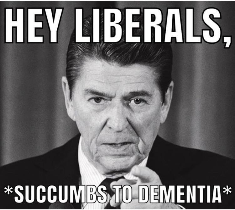 This meme is a darkly humorous image featuring a photo of former US President Ronald Reagan with a stern expression. The text at the top reads "Hey Liberals," and the bottom text says "Succumbs to Dementia." The meme is likely intended to be ironic or sarcastic, implying that the person being addressed is so liberal that they are so out of touch with reality that they are literally succumbing to dementia.