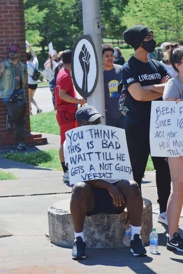 This meme is an image of a person sitting on the ground with their back to the camera, wearing a "I Can Read" sign. The sign is being held up by another person standing behind them, who is also wearing a "I Can Read" sign. The text on the sign reads "I can read" but is actually written in a childlike, scribbled handwriting.