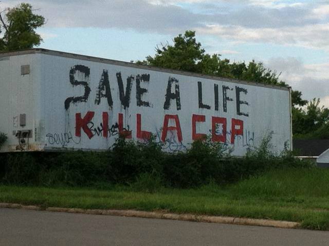 This meme is a photo of a graffiti-covered dumpster with the phrase "Save a life, kill a cop" painted on it. The phrase is written in a messy, hand-painted style, with the words "Save a life" written in bold, red letters and "kill a cop" written in smaller, blue letters underneath. The phrase is a darkly humorous and provocative commentary on the relationship between law enforcement and social justice.