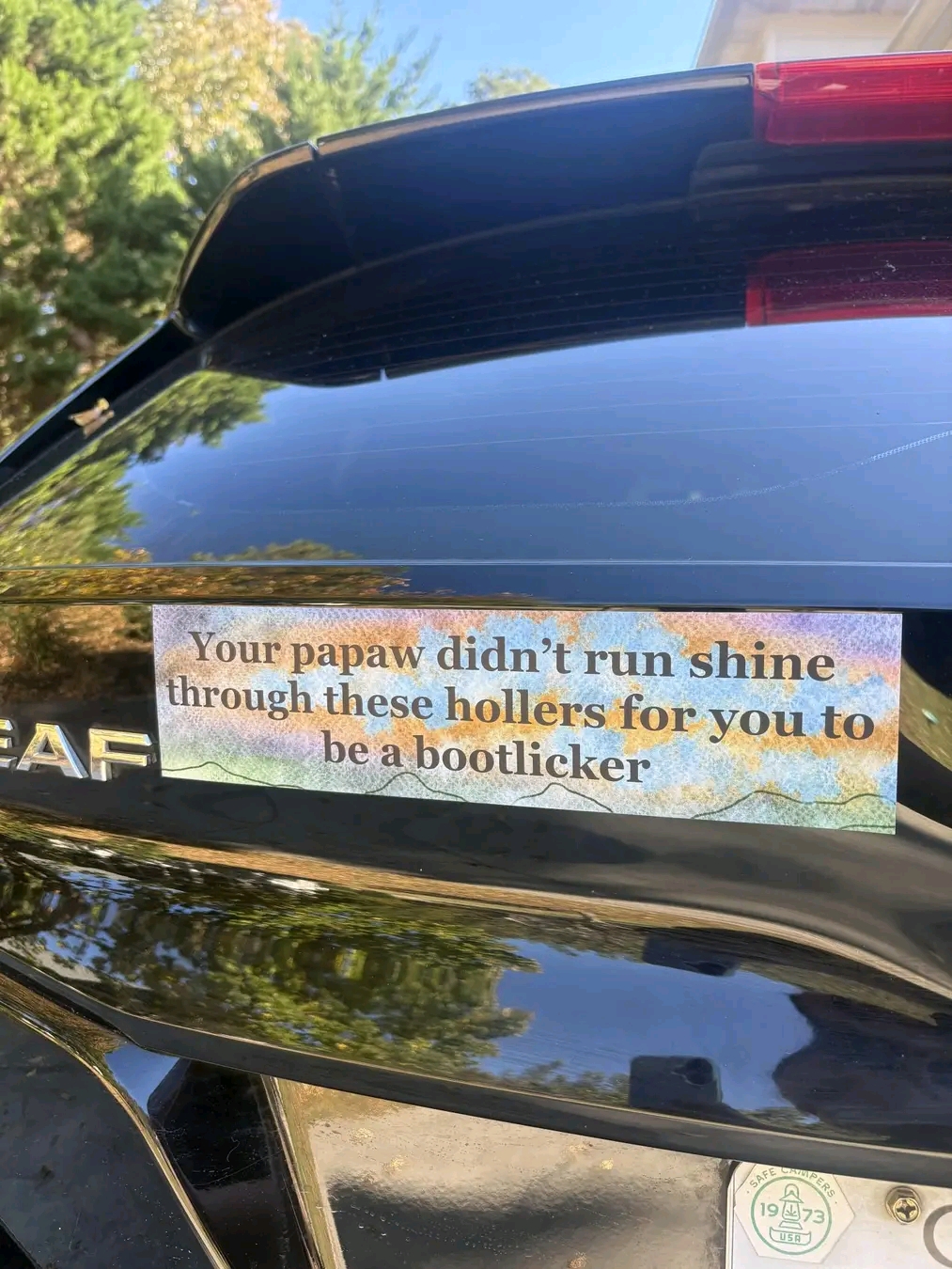 The meme is a humorous anti-cop sentiment, with the image of a bumper sticker that reads: "Your papaw didn't run through these hollers for you to be a bootlicker." The text is a playful, tongue-in-cheek way of express...