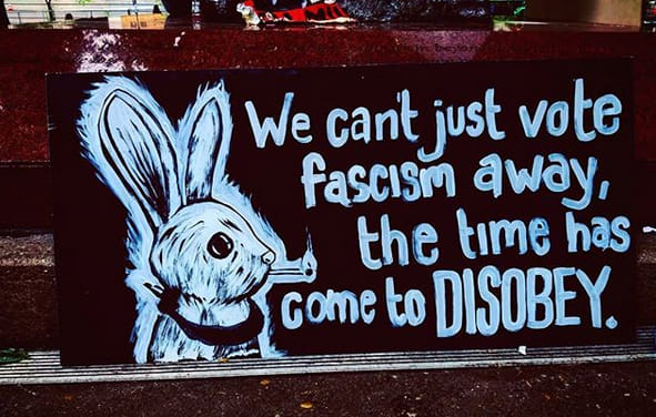 This meme is a humorous image featuring a cartoon rabbit, likely from the popular "Wascally Wabbit" series, with a caption that reads: "We can't just vote him out, we have to riot." The text is a satirical commentary on the 2020 US presidential election, implying that the only way to ensure a certain candidate's defeat is through violent protest, rather than voting.