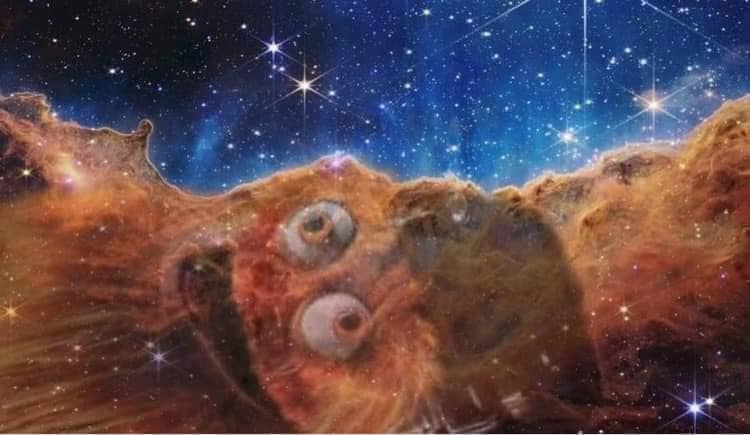The meme is a humorous image of the Hubble Space Telescope's Deep Space Image of the Carina Nebula. The image has been edited to include a cartoon-like, wide-eyed, and surprised face with an open mouth. The text "I can see your face now" is superimposed over the image.