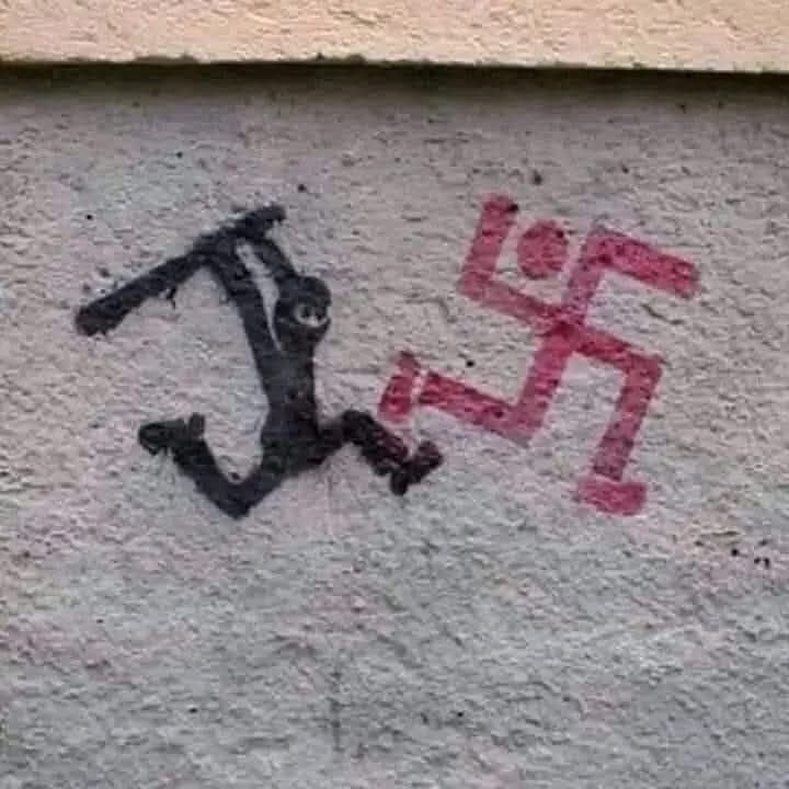 The meme features a black-and-white image of a stick figure holding a hammer and standing on a swastika. The swastika is a symbol of the Nazi Party and is often associated with white supremacy. The stick figure is meant to be ironic or satirical, as it's a simple and childish representation of a person being anti-Nazi.
