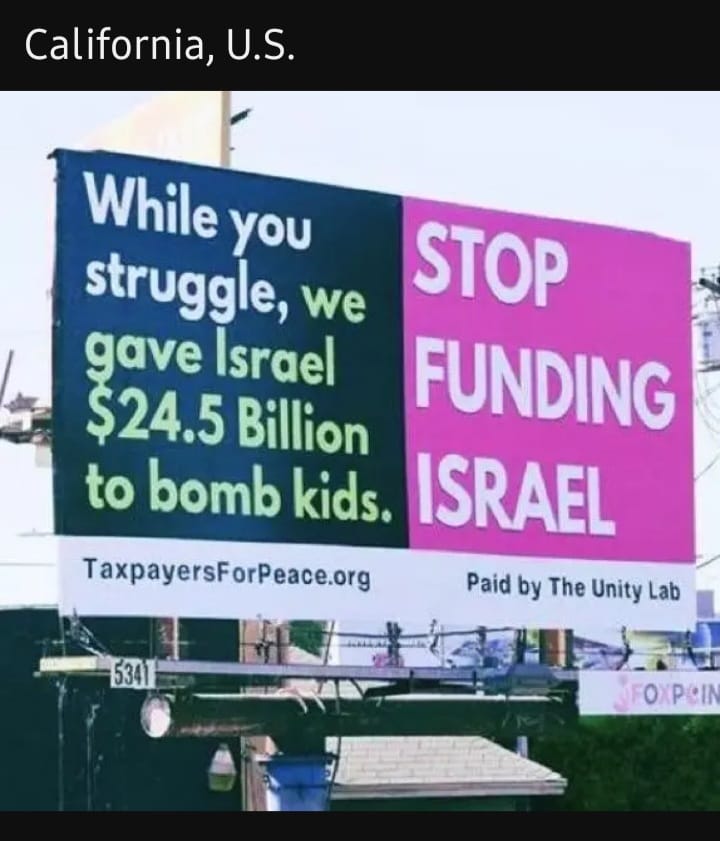 This meme is a photo of a protest sign in California, USA. The sign is divided into two sections: the left side says "While you struggle, we gave Israel $24.5 billion to bomb kids" and the right side says "Stop funding Israel". The sign is a protest against the US government's funding of Israel's military actions in the Middle East.