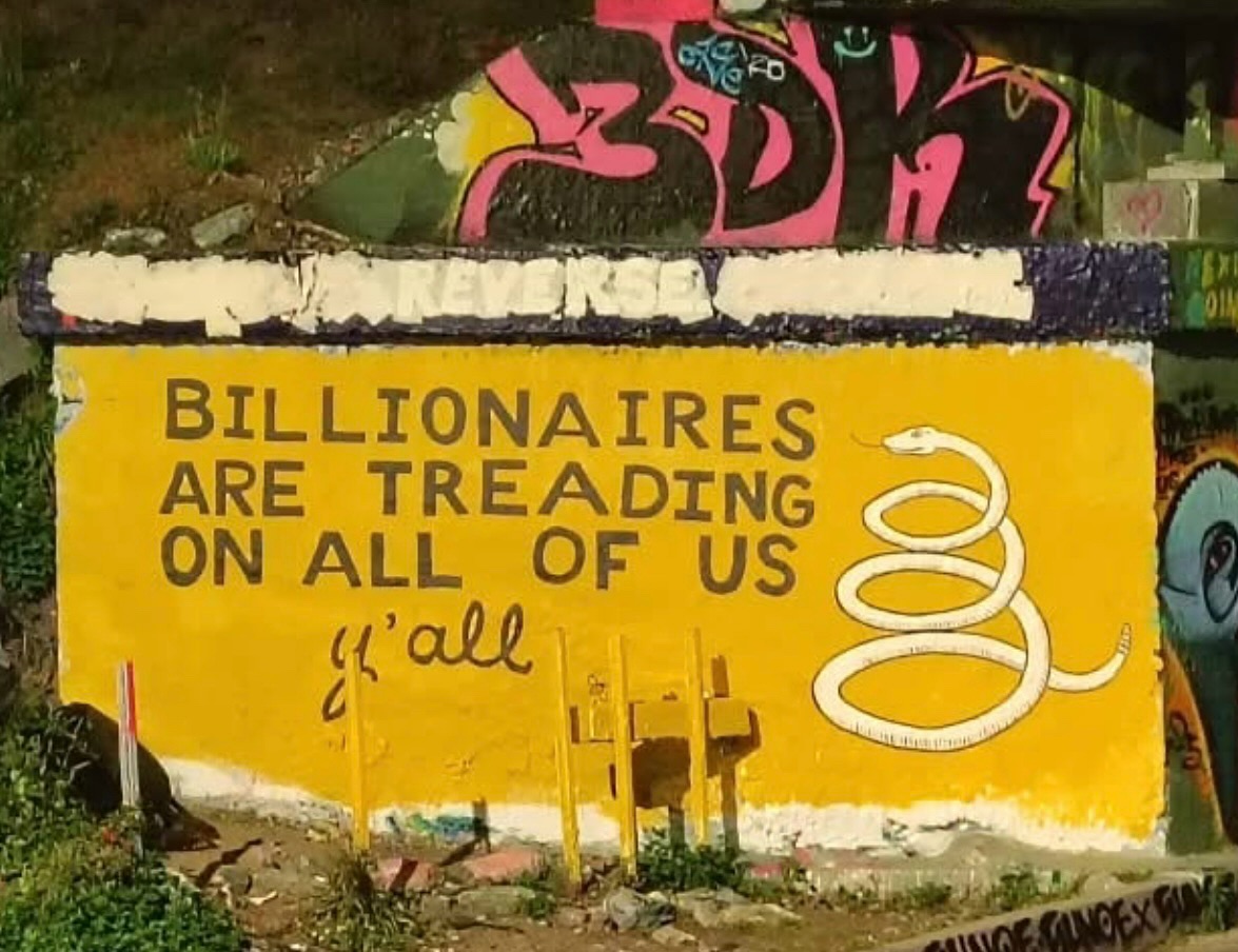 The meme is a humorous image that depicts a large, sprawling mural or graffiti on a wall. The text "Billionaires are treading on all of us" is written in bold, block letters, and is accompanied by a large, cartoonish snake that appears to be coiled around the text.
