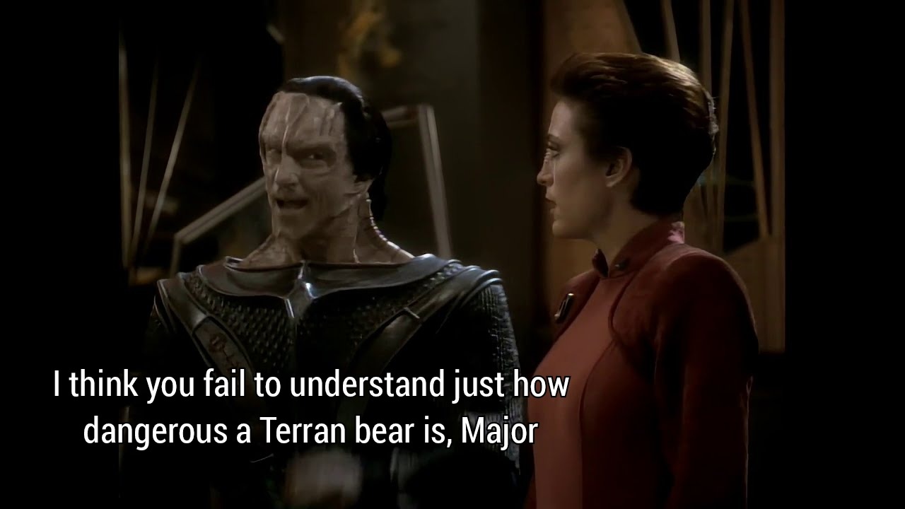 The meme is an image from the TV show Star Trek: Deep Space Nine, featuring characters from the show. The image shows the character of Ossar, a member of the Chakal, and the character of Kass , who is a member of the Chakal. The text that appears in the image is: "I think you fail to understand just how dangerous a Terran bear is, Major."