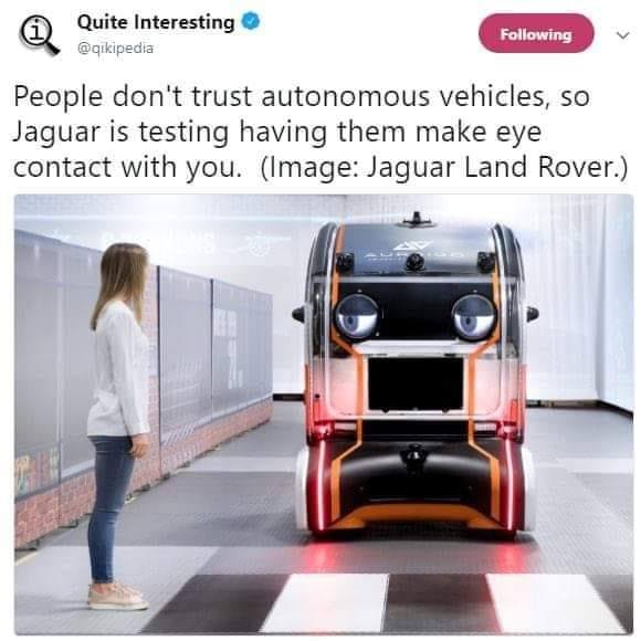 This meme is a joke about the autonomous vehicles developed by the company Jaguar Land Rover. The image shows a person standing in front of a futuristic-looking vehicle with a screen displaying a cartoonish face. The text above the image reads: "People don't trust autonomous vehicles, so Jaguar is testing one with a face that makes eye contact."
