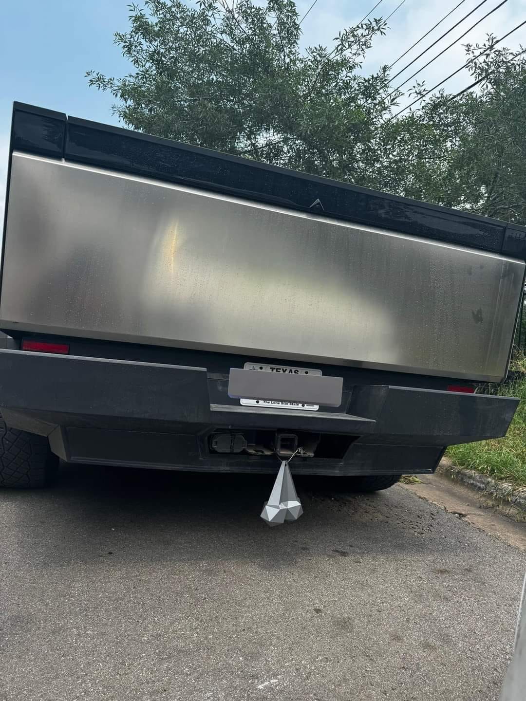 This meme is a photo of the back of a Tesla Cybertruck, with a trailer attached to it. The trailer is shaped like a giant, flat, metal rectangle, and it's being pulled by the Cybertruck. The text "I can see for miles and miles and miles" is written across the trailer, referencing the classic song "I Can See for Miles" by The Who.