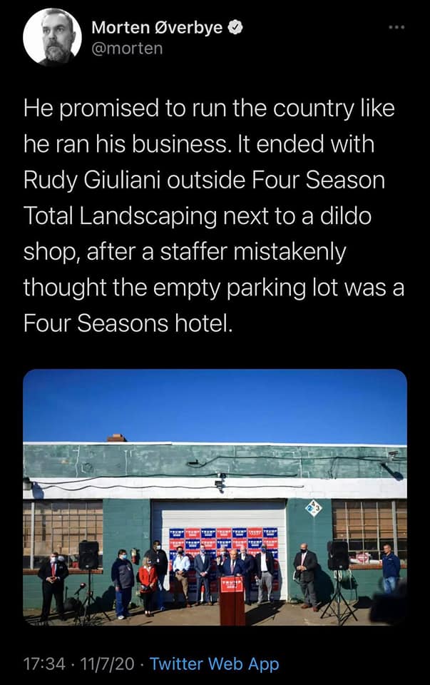 The meme is a photo of a group of people standing in front of a building, likely a campaign event. The text above the image reads: "He promised to run the country like he ran his business. It ended with Rudy Giuliani outside Four Seasons Total Landscaping next to a dildo shop, after a staffer mistakenly thought the empty parking lot was a Four Seasons hotel."