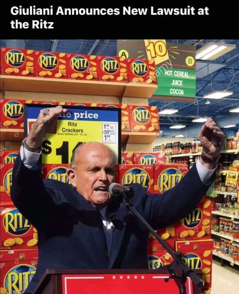 This meme is a humorous image of Rudy Giuliani, a former lawyer and politician, standing in front of a large display of Ritz crackers at a grocery store. The image is captioned "Giuliani announces new lawsuit at the Ritz" and is meant to be a play on words, as "the Ritz" can also refer to a luxury hotel, but in this case, it's a grocery store with a prominent display of Ritz crackers.