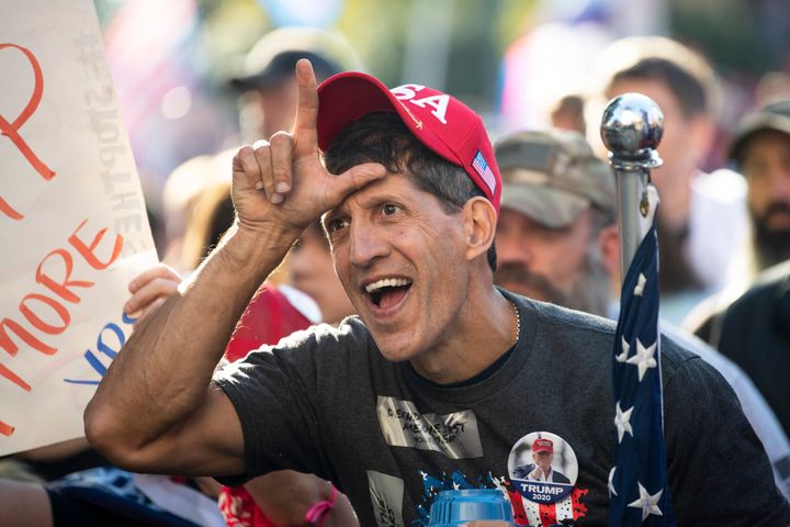 The meme features a photo of a person wearing a "Make America Great Again" (MAGA) hat, with their hand raised in a "V" shape for victory. The image is captioned "I just got a new job" and is likely meant to be humorous, implying that the person is celebrating their new job with a victory gesture. The tone is likely sarcastic, suggesting that the person is not actually celebrating a new job, but rather making a joke about their job search.