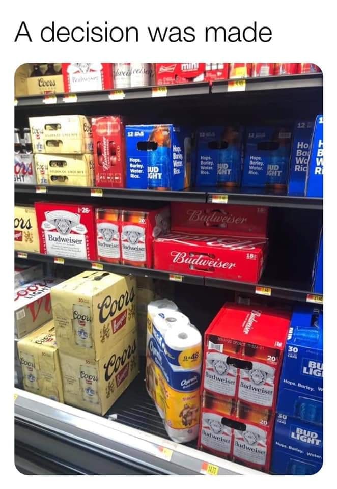 This meme is a humorous image of a grocery store shelf, but instead of the usual products, it's filled with cases of beer and other adult beverages, with a single roll of toilet paper in the middle of the shelf. The text at the top of the image reads "A decision was made". The joke is that in times of scarcity or shortage, the most essential item (in this case, toilet paper) is often prioritized and placed on the shelf in a visible and prominent location.
