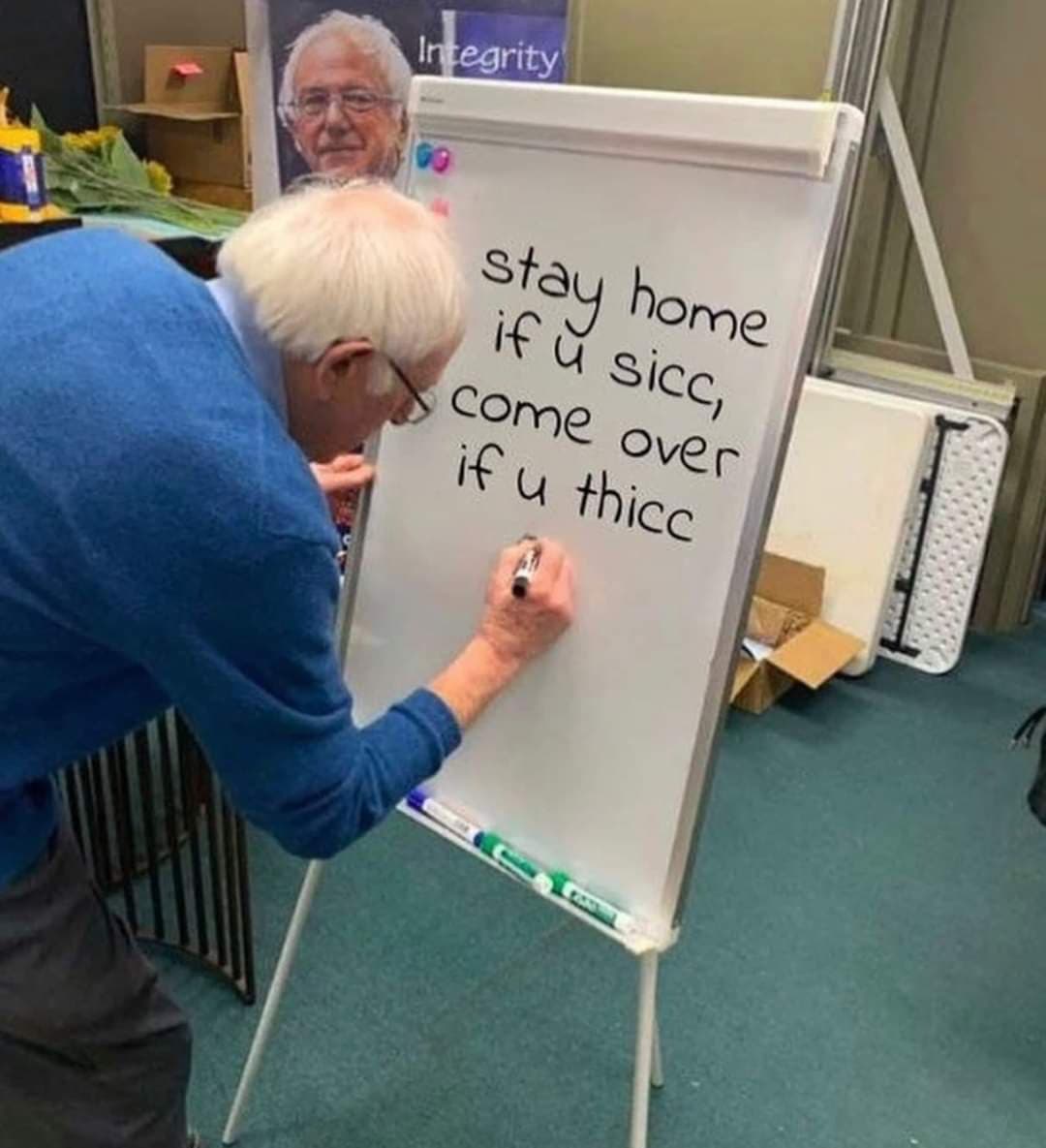 This meme is a photo of Bernie Sanders, a former US presidential candidate, sitting at a desk with a sign behind him that reads "Stay safe, stay home, stay sane". The image is captioned with a humorous phrase that is a play on words, using internet slang to create a humorous and ironic message. The phrase is: "Stay home, if you're sick, come out, if you're not sick, go out and get sick".