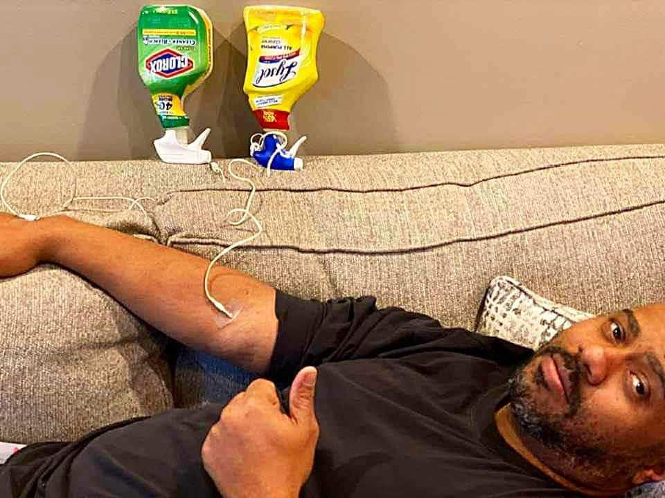 The meme features a photo of a person lying on a couch, with two bottles of cleaning products, Lysol and Clorox, sitting on the couch next to them. The bottles have been hacked to have USB ports, and the person is plugging their phone into them to charge. The text "I just charged my phone with bleach" appears on the screen.
