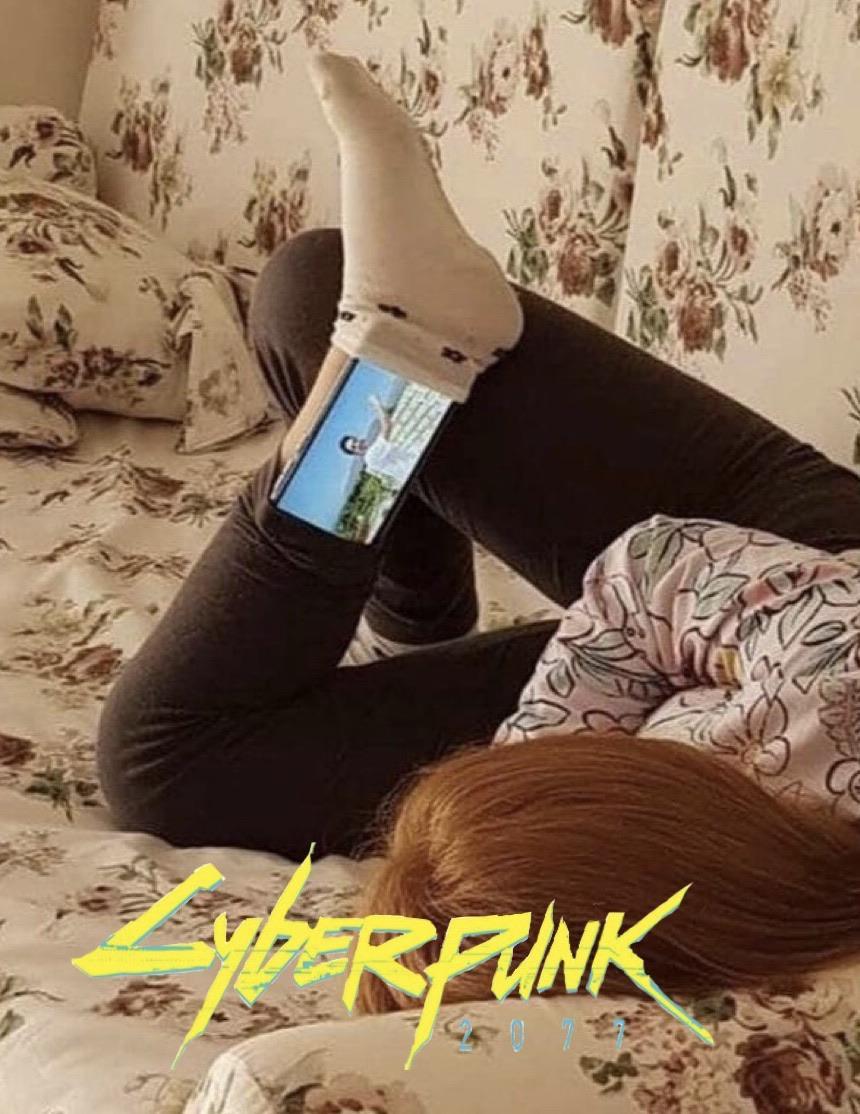 This meme is a picture of a person sitting on a couch with their legs up and a phone in their hand, but their legs are not actually up - they're being held up by a giant screen displaying a video game, specifically the game "Cyberpunk 2077". The text "Cyberpunk 2077" is overlaid on the image, and the caption "My legs are fine, I swear" is written in a humorous tone.