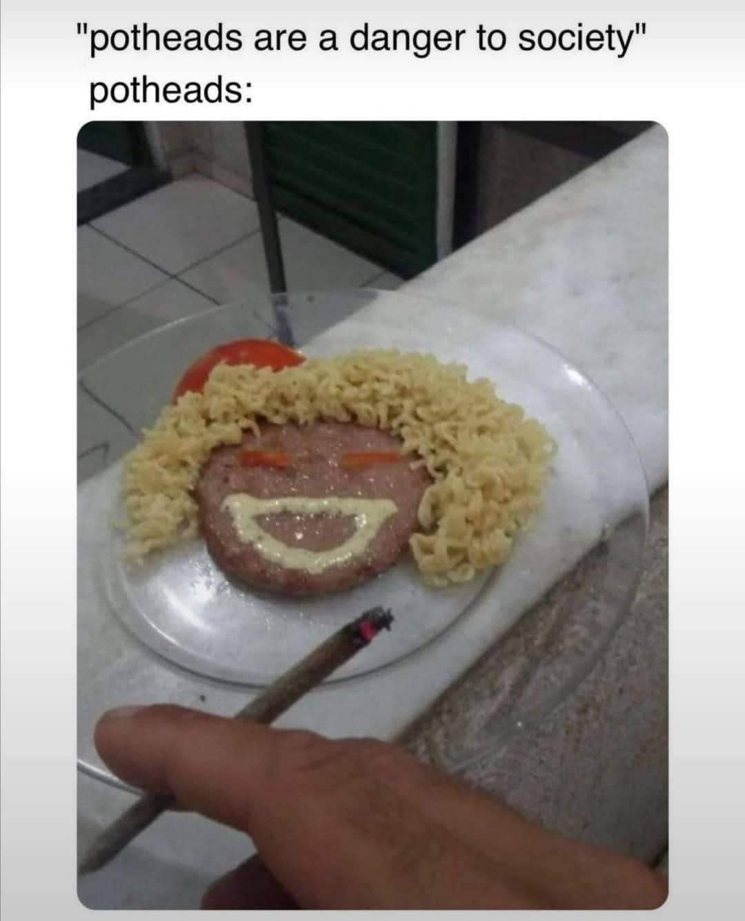 This meme is a humorous commentary on the stereotype that "potheads" are a danger to society. The image shows a person's hand holding a lit joint, with a plate of food in front of them. The text above the image reads, "potheads are a danger to society" but the image shows a person eating a plate of spaghetti with a smiley face made of meatballs, indicating that they are actually a danger to their own stomach.