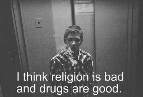 This meme is a black-and-white image of a person with a cigarette in their mouth and a faint, ghostly image of a person in the background. The text "I think religion is bad and drugs are good" appears at the bottom of the image in a simple, white font. The image is likely a reference to a scene from the 1999 film "The Blair Witch Project", where the character of Daniel is seen smoking and has a ghostly image of himself in the background.