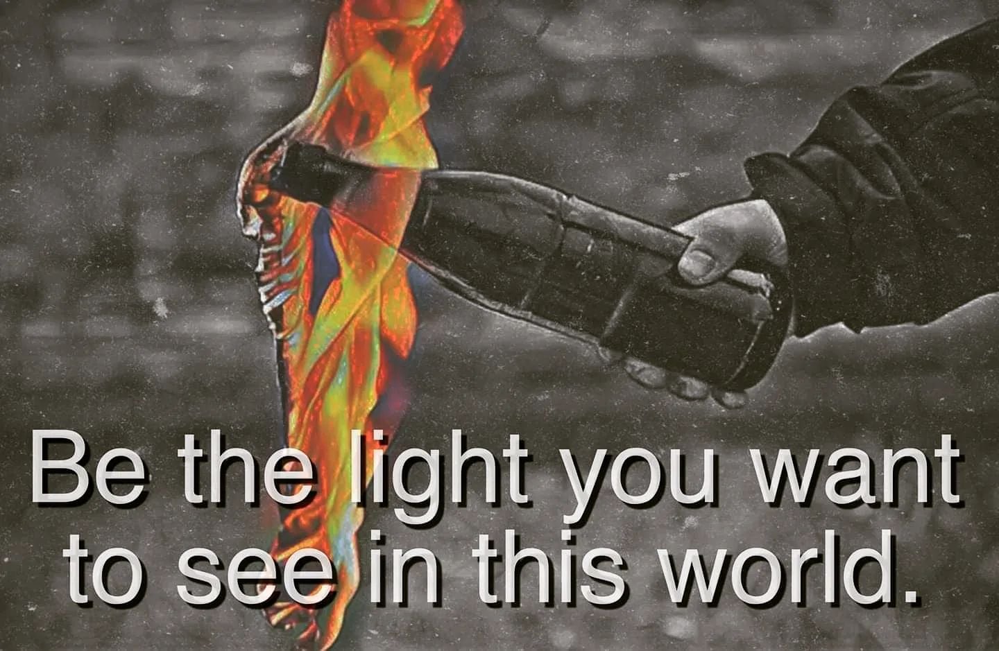 The meme features a person's hand reaching out to touch a flame, with the text "Be the light you want to see in this world." The image conveys a message about being a positive force in society, rather than simply desiring others to be so. The person's hand reaching out to touch the flame suggests that they are actively trying to be that light.