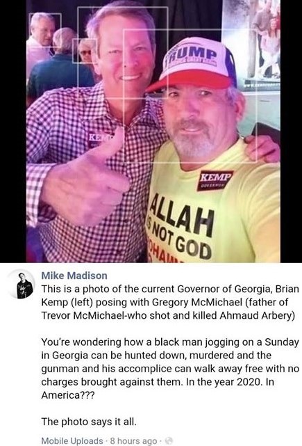 The meme features a photo of Georgia Governor Brian Kemp posing with Gregory McMichael, the father of the man who killed Ahmaud Arbery. The image is accompanied by a text that reads, "You're wondering how a black man can be hunted down, murdered and the gunman and his accomplice can walk away with no charges in 2020. In the year 2020."