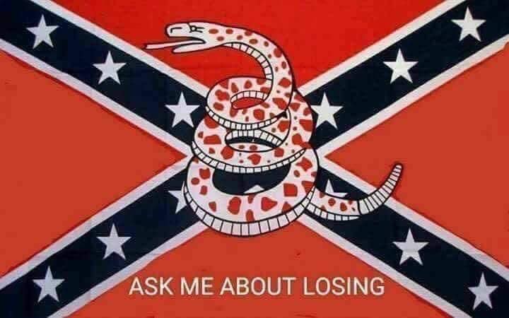 The meme is a humorous reference to the famous "Ask Me About My War" sign, but with a Southern American twist. The image features a Confederate flag with a snake coiled around the cross, and the text "Ask Me About Losing" appears below it. The meme is likely meant to poke fun at the idea of a Southern American person being proud of their war history, but instead of being proud of their wins, they're only good at losing.