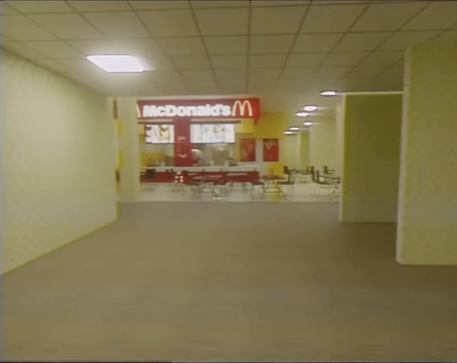 This meme is a screenshot of a desolate, abandoned shopping mall. The image shows a long, empty hallway with a few scattered chairs and a McDonald's restaurant in the distance. The text "I'm lovin' it" is written in a bold, red font above the restaurant, a sarcastic reference to the company's famous advertising slogan.
