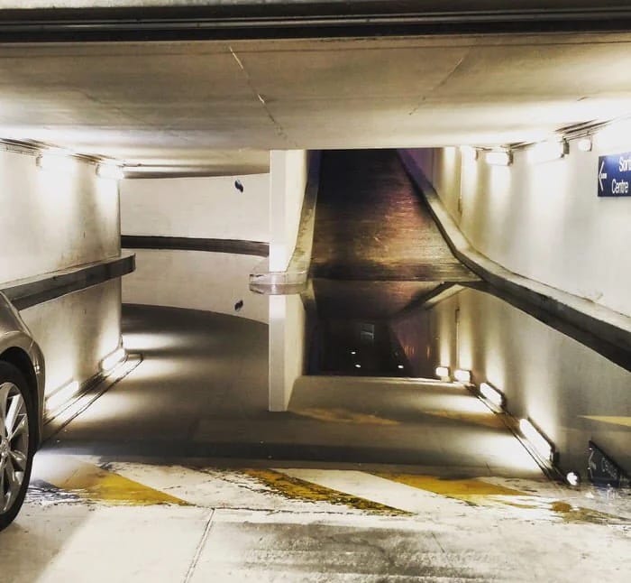 This meme is a photo of a dark and empty parking garage, with a faint image of a car's headlights in the distance. The text "I've been here for 5 minutes" appears on a sign in the background, implying that the person is feeling frustrated and stuck. The meme is likely humorous because it pokes fun at the common experience of feeling impatient or stuck in a situation.