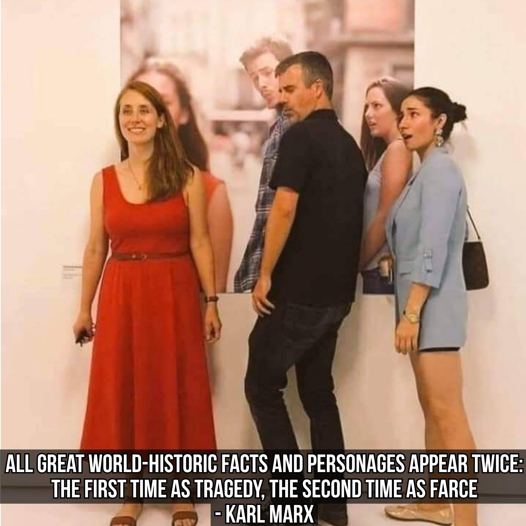 This meme features a photo of a woman in a red dress standing in front of a large poster of a cityscape, with a group of people behind her. The text overlay reads: "All great world-historic facts and personages appear twice: the first time as tragedy, the second time as farce." The quote is attributed to Karl Marx, but the image itself is a humorous twist on the idea of a famous person's photo being used in an unexpected way.