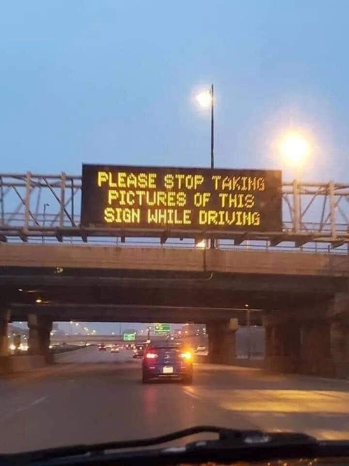 This meme is a photo of a digital highway sign that is normally used to display traffic updates or warnings. However, in this case, the sign is displaying a humorous message that is not related to traffic at all. The text on the sign reads: "Please stop taking pictures of this sign while driving."