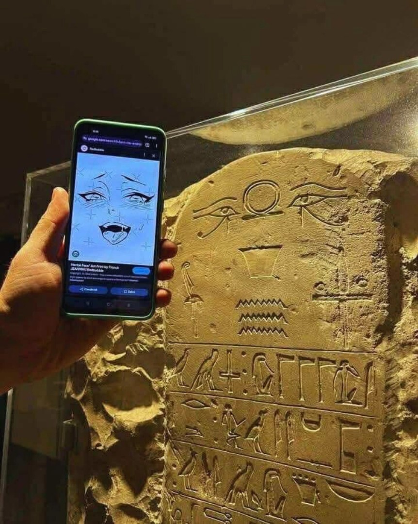 The meme is a humorous image of a ancient Egyptian tomb wall with a modern, anime-style face carved into it. The image is captioned "Ancient Egyptian tomb walls: 'I'm not mad, I'm just... 3000 BC'".