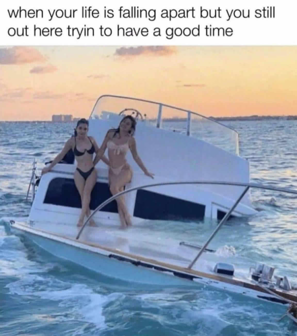 The meme is a humorous image of two women in bikinis standing on a sinking boat. The text above the image reads: "when your life is falling apart but you still try to have a good time". The image is a playful commentary on the human tendency to find joy and make the most of situations, even when things are not going well.