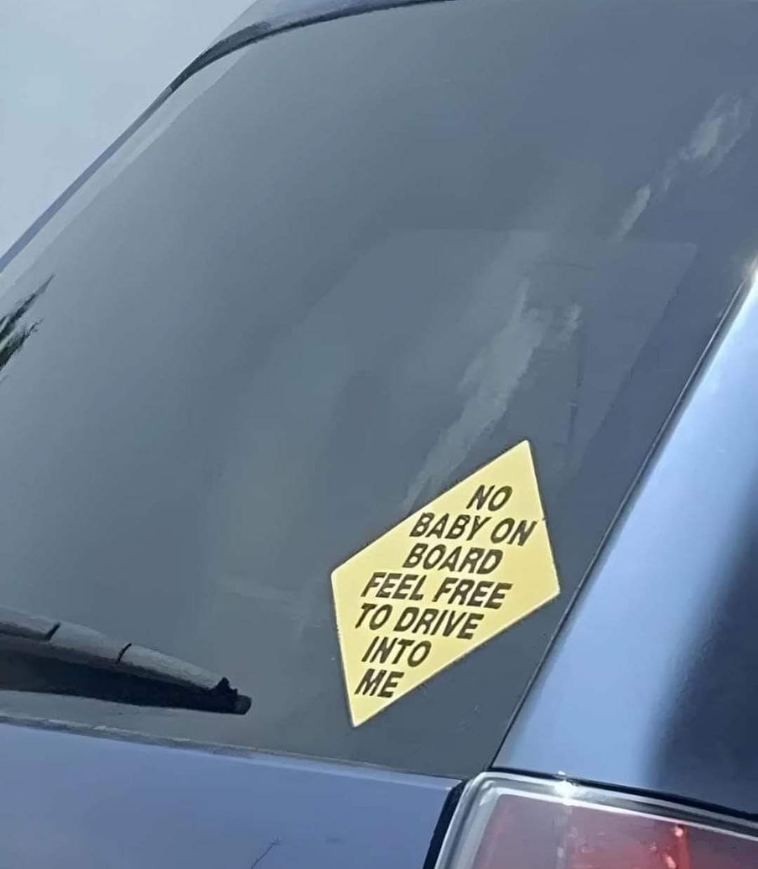 This meme is a humorous warning sticker for a car. The sticker reads: "No baby on board, but feel free to drive into me." It's a sarcastic and ironic take on the traditional "Baby on Board" stickers that are often seen on cars to alert other drivers to the presence of a child in the vehicle. The sticker's tone is playful and tongue-in-cheek, implying that the driver is not concerned about the safety of their own vehicle, let alone the safety of others.