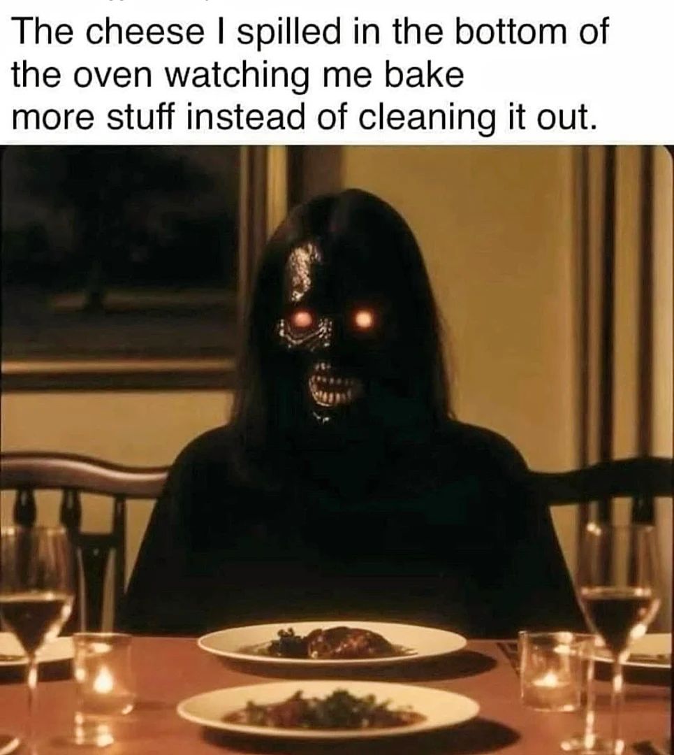 This meme is a humorous image of a person sitting at a dinner table, with a plate of food in front of them. The text above the image reads, "The cheese I spilled in the bottom of the oven watching me bake more stuff instead of cleaning it out." The image is likely a darkly comedic representation of someone who is avoiding cleaning up after themselves, and is instead choosing to indulge in food instead of cleaning the oven.