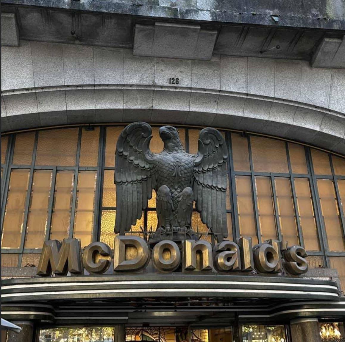 The meme is a photo of a McDonald's restaurant with a large, stone eagle statue on top of the building. The text "I love McDonald's" is written above the eagle, but it's actually misspelled as "I luv McDonald's". The meme is likely poking fun at the eagle's awkward, poorly spelled sign, implying that even a majestic symbol like an eagle can be flawed and ridiculous.