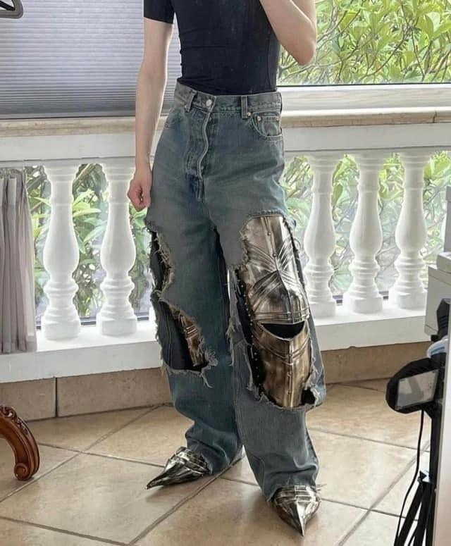 This meme is an image of a person wearing a pair of ripped jeans with a large, shiny metal plate attached to one of the legs. The plate is shaped like a medieval knight's armor and is attached to the jeans in a way that looks like it was hastily glued on. The text "I'm not lazy, I'm just conserving energy" appears at the top of the image.