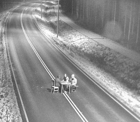 The meme features a black-and-white photograph of a man sitting at a desk in the middle of a deserted road. The text "I can explain" appears on the desk, implying that the man is trying to explain something to someone, but is instead being ignored or dismissed by the person he's addressing.