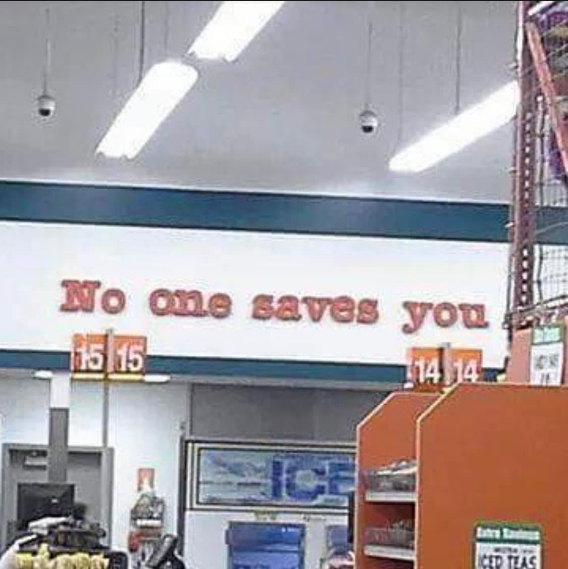 This meme is a screenshot of a store's security sign that reads "No one saves you" in a bold, red font. The sign is placed above a cash register and is likely intended to be a humorous or ironic warning to customers. The text is a play on the common phrase "no one can save you" and is meant to be a tongue-in-cheek warning to customers who might be trying to save a few dollars by not purchasing a security camera.
