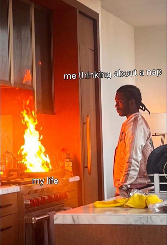 The meme features a person sitting in a chair, looking at a kitchen fire that has suddenly erupted. The text "me thinking about a nap" is placed above the person, while "my life" is written below the fire. The image is humorous because it exaggerates the idea that a simple thought about a nap can lead to chaos in one's life.