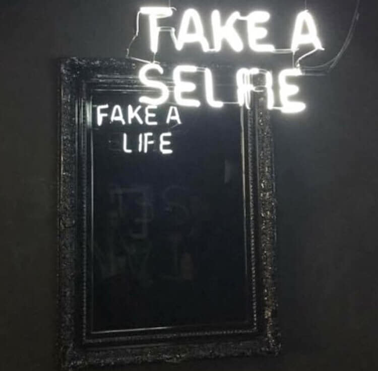 The meme is a screenshot of a TikTok video where a user is lip-syncing to a song with the lyrics "I'm just faking smiles" and "I'm just pretending". The user is also holding a sign that says "I'm just faking it" and "I'm just pretending". The meme is likely poking fun at the idea of pretending to be happy or fulfilled when you're actually not.