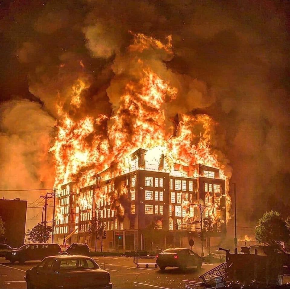 The meme depicts a large, burning building with flames engulfing the top floors. The image is captioned "when you finally get that one bill paid off".