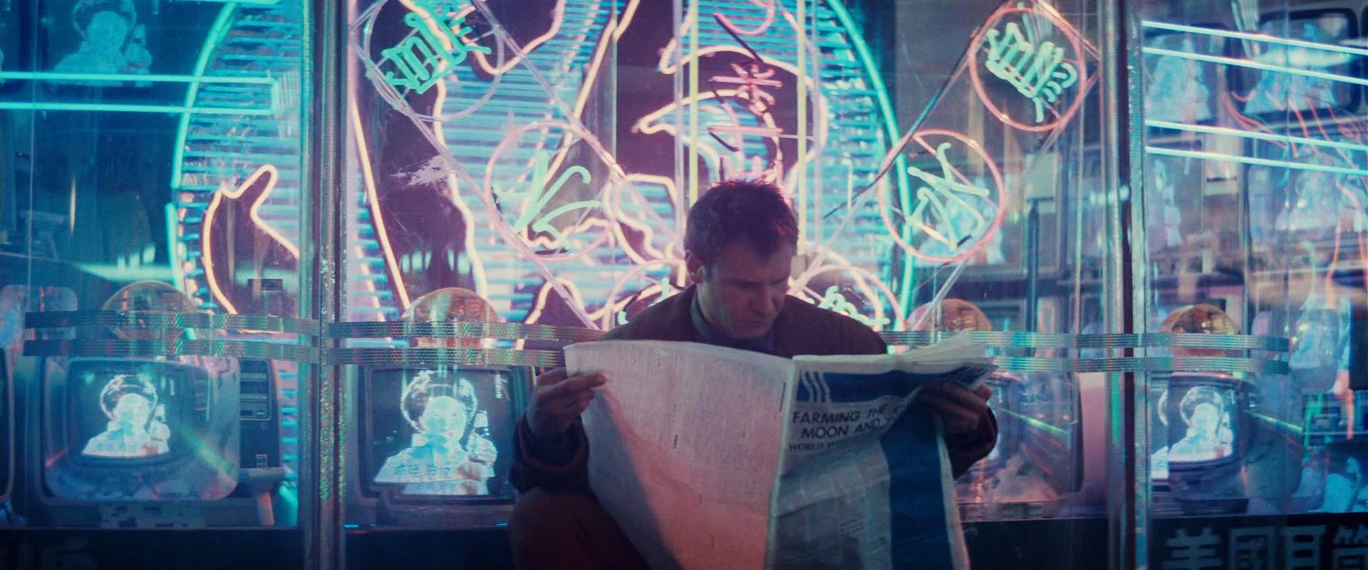 The meme features a person sitting in a dimly lit, futuristic setting, surrounded by neon lights and screens displaying a futuristic cityscape. The image is captioned "I just realized I'm not even living in the future, I'm just living in a 90s sci-fi movie".