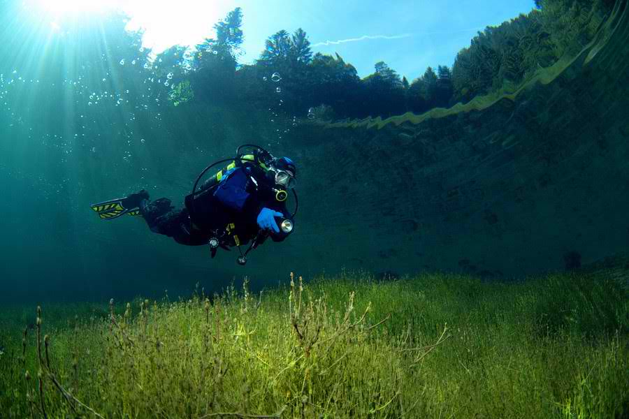 This meme features a person in a scuba diving outfit, floating above a lush underwater landscape. The image is captioned "When you finally get to the meeting after being in the email thread for weeks".