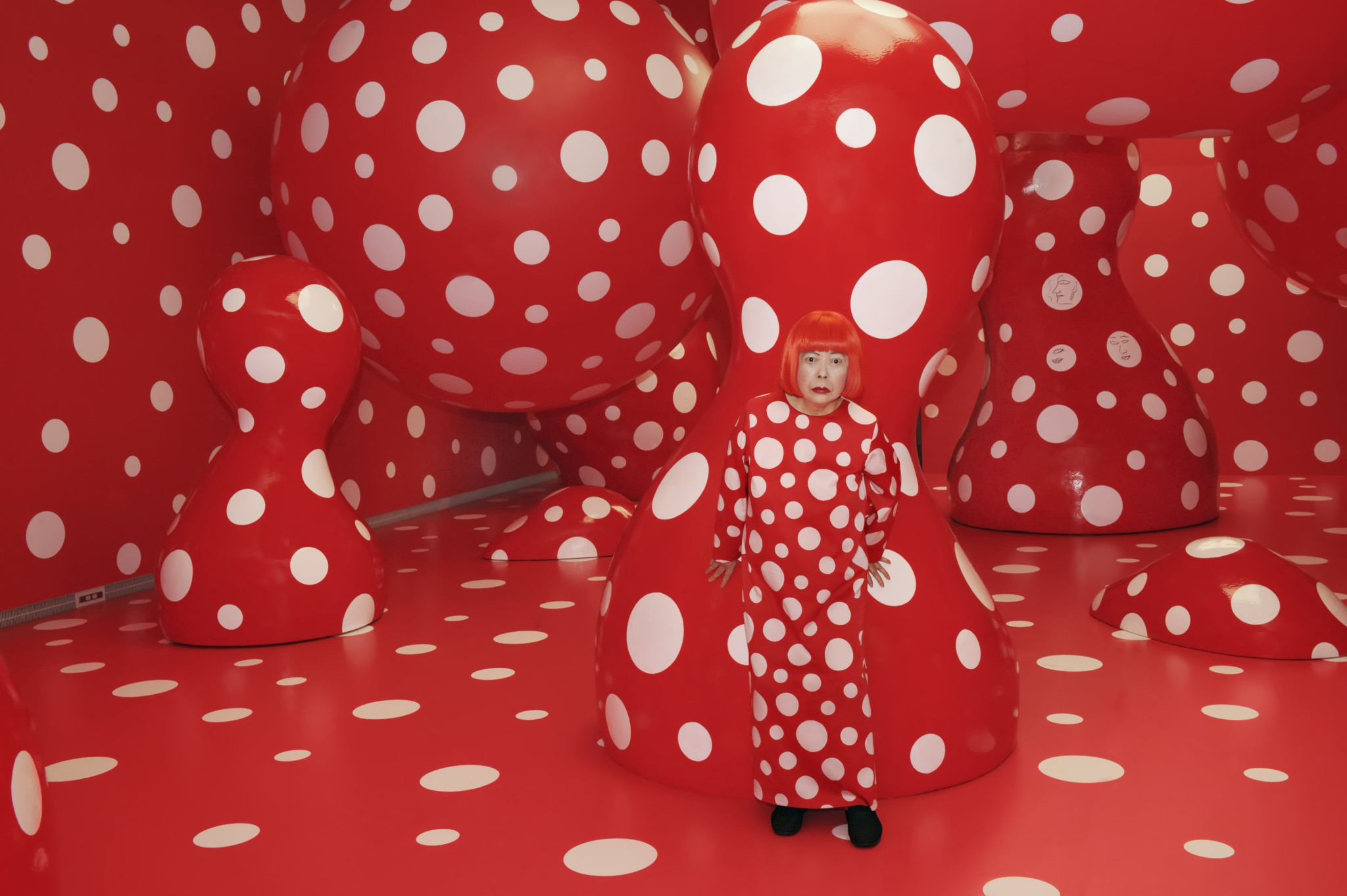 The meme is an image of a woman (Kojo Kometo) with a red wig and a red dress, standing in a room filled with red and white polka dots. The image is a recreation of a 2013 Yayoi Kusama retrospective at the Museum of Modern Art in New York.