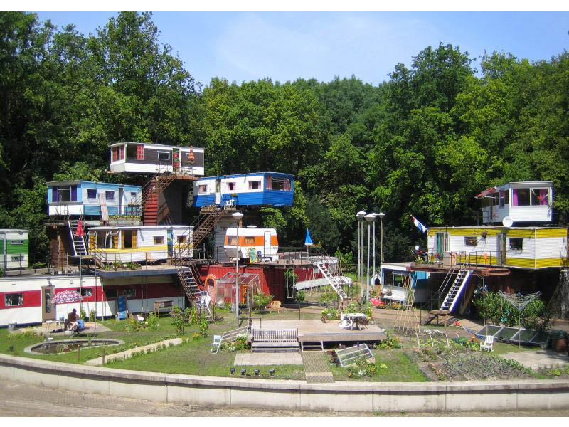 The meme is an image of a colorful, ramshackle village built on a hillside, with many small houses and gardens. The text "I can see my house from here" is often associated with this image, implying a sense of pride an...